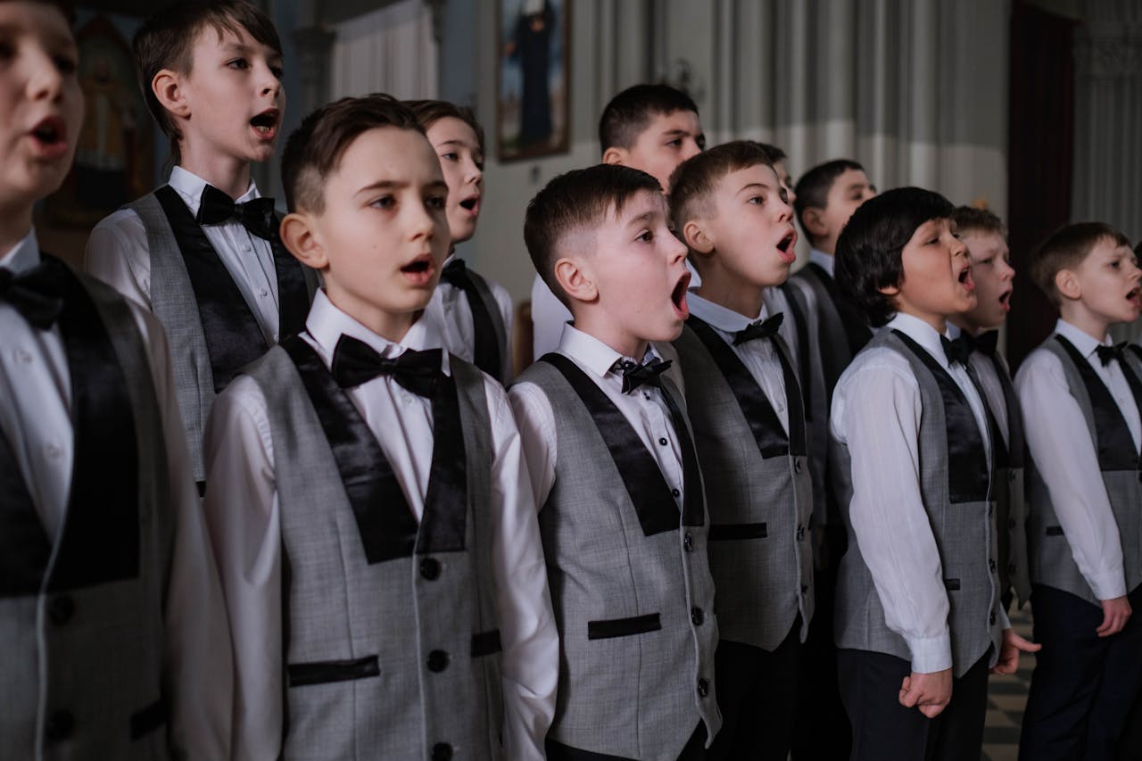 Boys perform in a school choir dressed in formal uniforms, focused on singing.